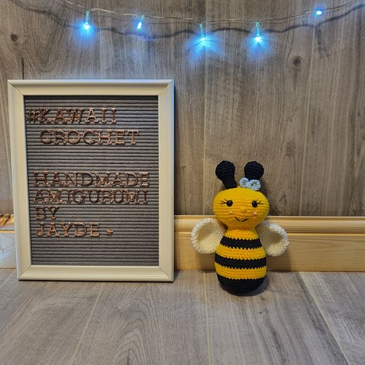 A hand-crocheted amigurumi bee in yellow and black stripes with cream wings