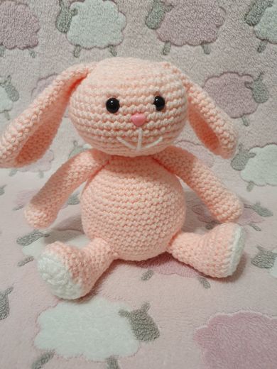 A hand-crocheted amigurumi bunny in pale pink