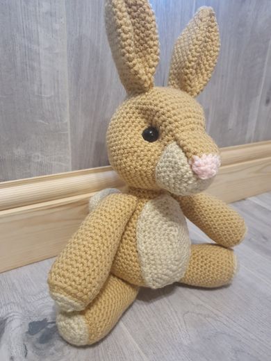 A hand-crocheted amigurumi hare with tall ears in tan and cream