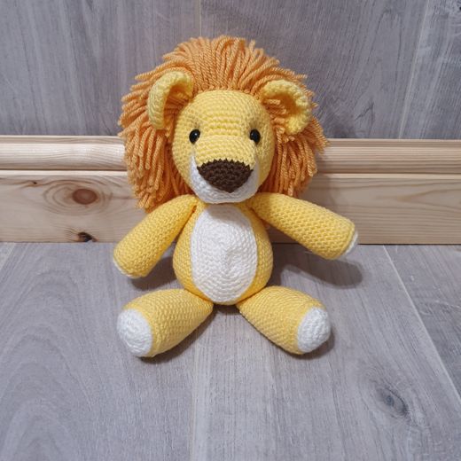 A hand-crocheted amigurumi lion with a fluffy orange mane
