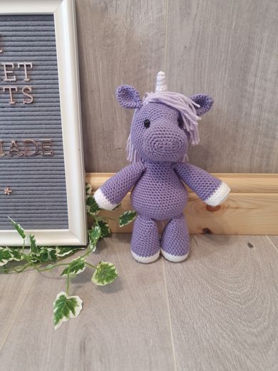 A hand-crocheted amigurumi unicorn in lilac and purple