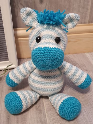 A hand-crocheted amigurumi zebra in blue and white stripes