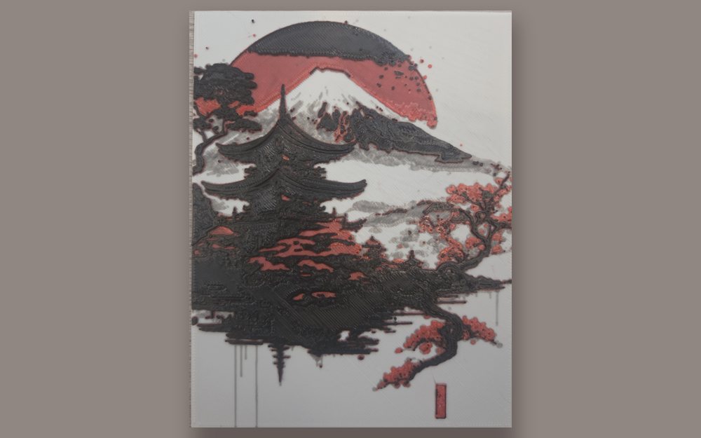 One of our picture plaques: a black, red and white layered print of a Japanese-style landscape, lying on a wooden table